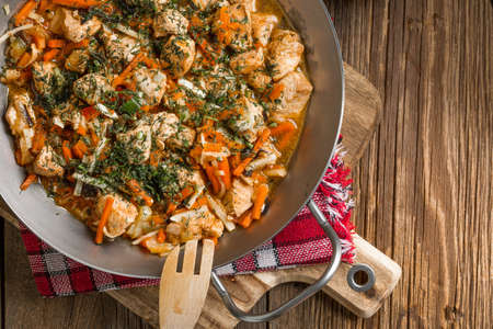 Fried chicken pieces with vegetables on a metal frying pan. Small depth of focus.の写真素材