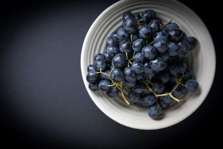 Dark grape in bowl on wooden table. Selective focus. Top view, copy space.
