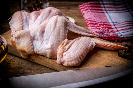 Fresh chicken wings on wooden board on table. Selective focus.の写真素材