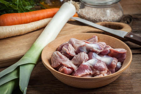Raw uncooked chicken gizzards (stomachs) in a wooden bowl.の写真素材