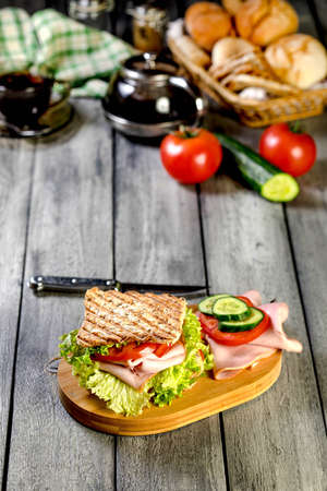 Sandwich with ham, cucumber, tomato and lettuce, with two layers of filling between three slices of toast.の写真素材