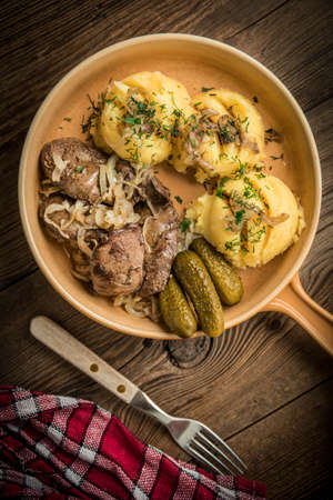 Fried chicken liver with onion served with mashed potatoes and pickled cucumber. Small depth of field. Top view.の写真素材