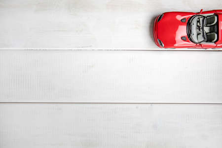 Small toy car on a white wooden background. Top view. Copy space.