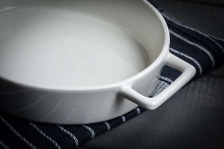 Empty dish for baking on a dark countertop. Dark light.の写真素材