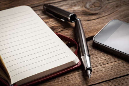 Opened blank notebook with elegant fountain pen on wooden background.の写真素材