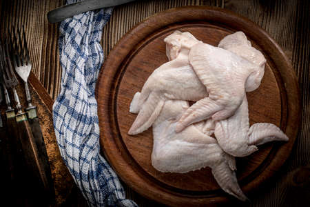 Fresh raw chicken wings on a cutting board on rustic table.の写真素材