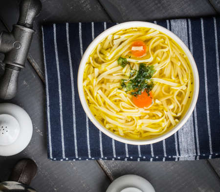 Tasty meat broth with noodles, carror and parsley in a plateの写真素材