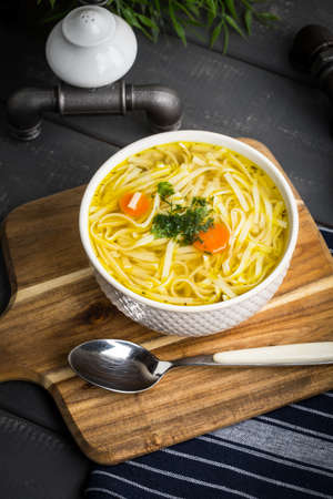 Tasty meat broth with noodles, carror and parsley in a plateの写真素材