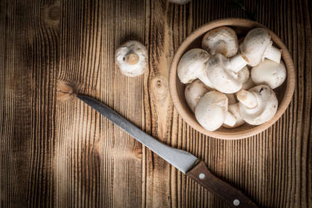 Fresh white champignon mushrooms in wooden bowl.の写真素材