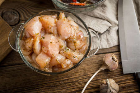 Raw chicken fillet breast cut into pieces and spiced in glass bowl. Small depth of field.の写真素材
