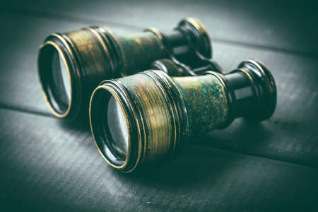 Old binoculars covered with patina on a gray wooden background.の写真素材