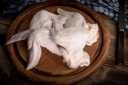 Fresh raw chicken wings on a cutting board on rustic table.の写真素材