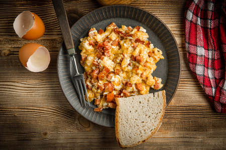 Scrambled eggs with sausage on wooden background. Top view.の写真素材