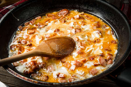 Scrambled eggs with sausage on wooden background.の写真素材