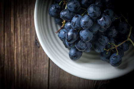 Dark grape in bowl on wooden table. Selective focus. Top view, copy space.の写真素材
