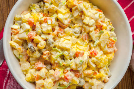 Salad with potato, corn, carrot, eggs and mayonnaise on wooden table. Shallow depth of field. Top view.の写真素材