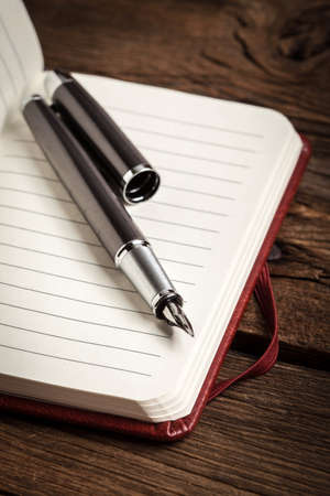 Opened blank notebook with elegant fountain pen on wooden background.の写真素材