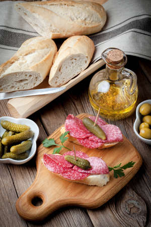 Spanish cuisine. Tapas with sliced sausage, salami, olives and parsley on a wooden table.の写真素材