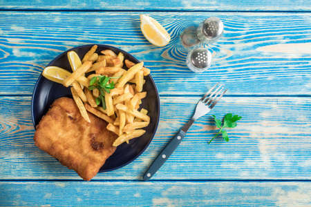 A piece of fried cod with fries on a plate. Top view.の写真素材