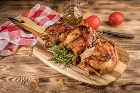 Pieces of roasted chicken on a wooden chopping board.