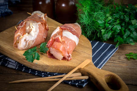 Raw chicken breast stuffed with champignon wrapped with bacon - ready to baked.の写真素材