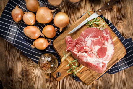 Raw pork shoulder on cutting board with knife.の写真素材