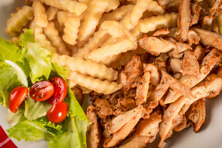 Greek gyros with fries and salad on plate.