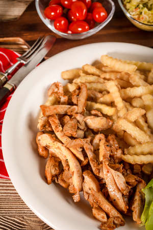 Greek gyros with fries and salad on plate.