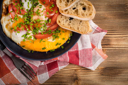 Homemade breakfast fried egg with tomato on wooden table.の写真素材