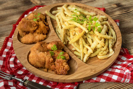 Crispy chicken nuggets with yellow bean on bamboo plate.