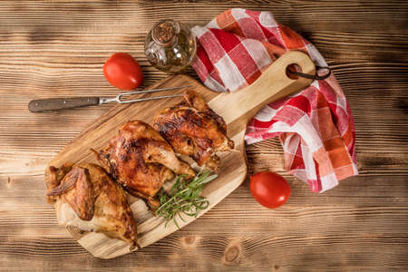 Pieces of roasted chicken on a wooden chopping board. Top view.の写真素材