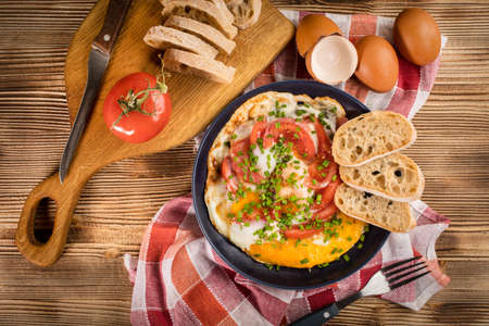 Homemade breakfast fried egg with tomato on wooden table. Top view.の写真素材