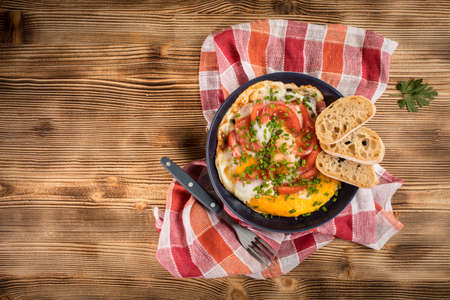 Homemade breakfast fried egg with tomato on wooden table. Top view.