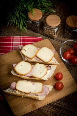 Sandwich with ham and smoked cheese on cutting board.の写真素材