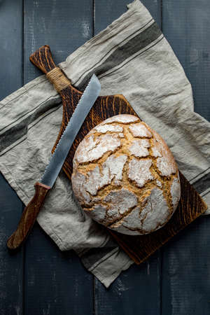 A loaf of fresh country bread on a chopping board.
