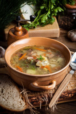 Pea soup with vegetables and bacon on a wooden table. Dark light.の写真素材