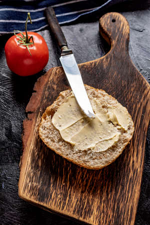 Slice of bread smeared with butter lying on a chopping board.