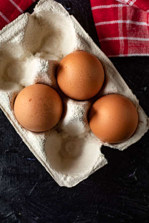 Fresh farm eggs on a wooden rustic background. Dark light.