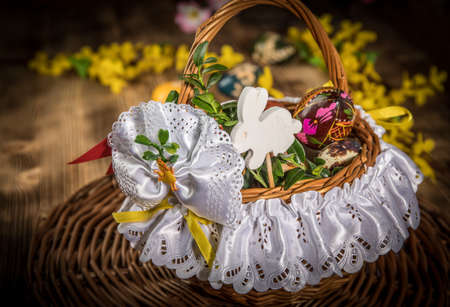 Traditional Easter basket with colored eggs on the wooden table.