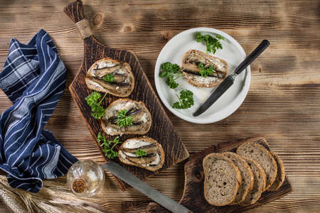 Sandwich with sprats on wooden table. Top view.