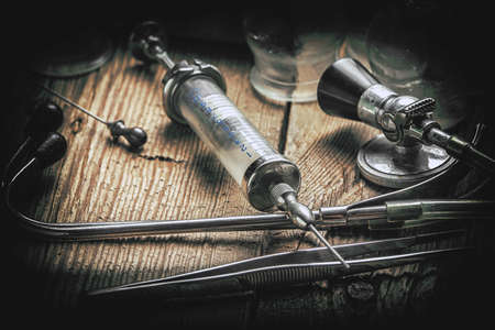 Retro syringe, stethoscope and medical cupping glass on a wooden table. Shallow depth of field....