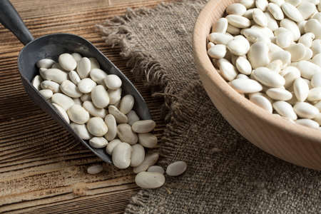 Dried white beans in a wooden bowl.