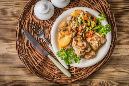 Chicken fillet with stewed vegetables on a white plate.の写真素材