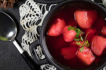 Red borscht soup in bowl on black background.