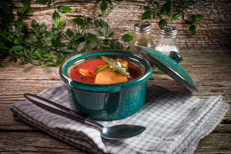 Red borscht soup in bowl on wooden background.