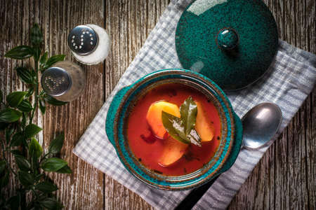 Red borscht soup in bowl on wooden background.