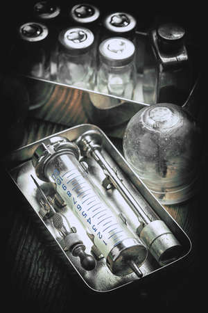 Retro syringe, stethoscope and medical cupping glass on a wooden table. Shallow depth of field....
