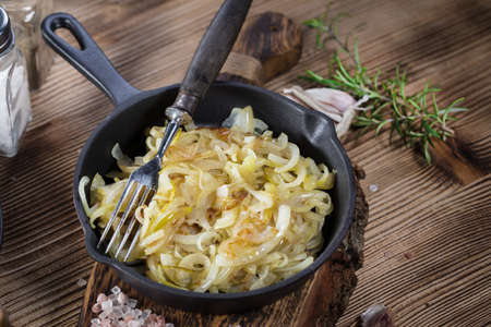 Fried onion in a cast iron skillet standing on a wooden countertop.の写真素材