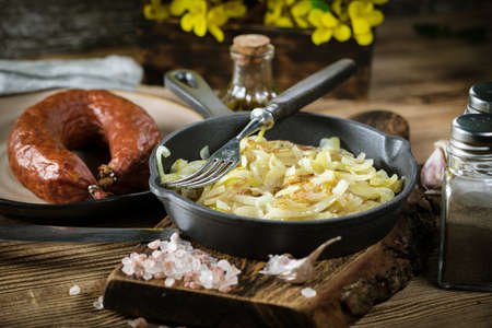 Fried onion in a cast iron skillet standing on a wooden countertop.の写真素材