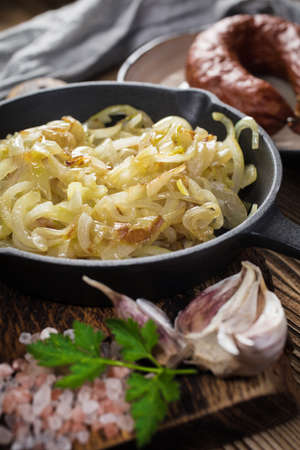 Fried onion in a cast iron skillet standing on a wooden countertop.の写真素材